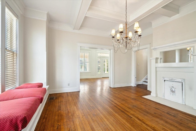 dining room featuring beamed ceiling, wood-type flooring, a chandelier, ornamental molding, and a high end fireplace