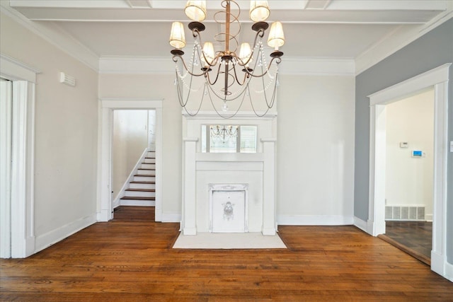 foyer entrance featuring beamed ceiling, ornamental molding, dark wood-type flooring, and a notable chandelier