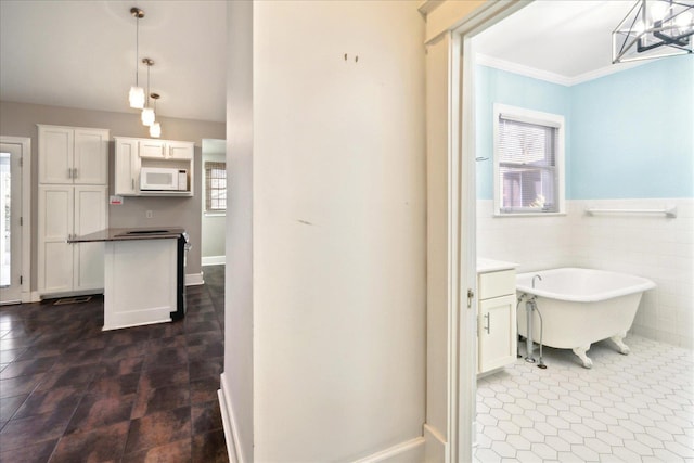 bathroom featuring crown molding, plenty of natural light, a bathing tub, and tile walls