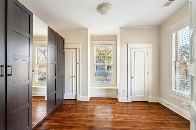 interior space with dark hardwood / wood-style flooring, crown molding, and multiple windows