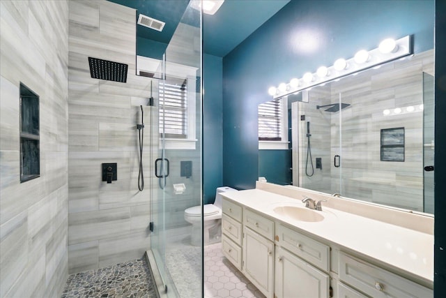 bathroom with tile patterned flooring, vanity, walk in shower, and toilet