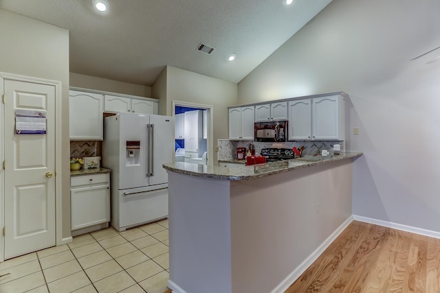 kitchen with white cabinetry, tasteful backsplash, kitchen peninsula, light stone countertops, and black appliances