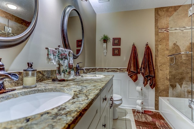 full bathroom featuring shower / bath combination with glass door, tile patterned flooring, vanity, toilet, and a textured ceiling