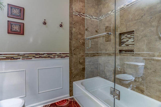 bathroom featuring combined bath / shower with glass door and toilet