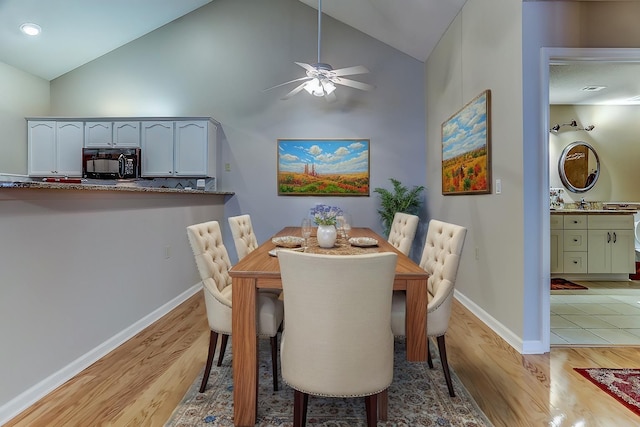 dining space featuring ceiling fan, high vaulted ceiling, and light wood-type flooring