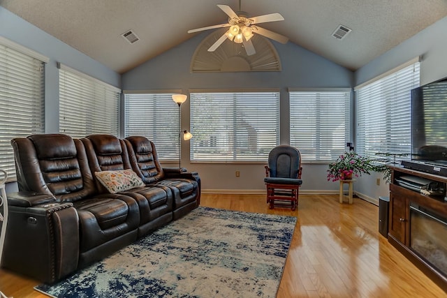 living room featuring lofted ceiling, a textured ceiling, ceiling fan, and light hardwood / wood-style floors