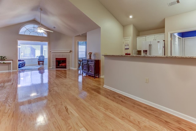 living room featuring vaulted ceiling, ceiling fan, a fireplace, and light hardwood / wood-style floors