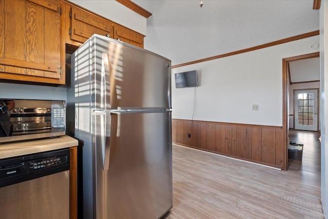 kitchen with crown molding, appliances with stainless steel finishes, a textured ceiling, and light hardwood / wood-style flooring