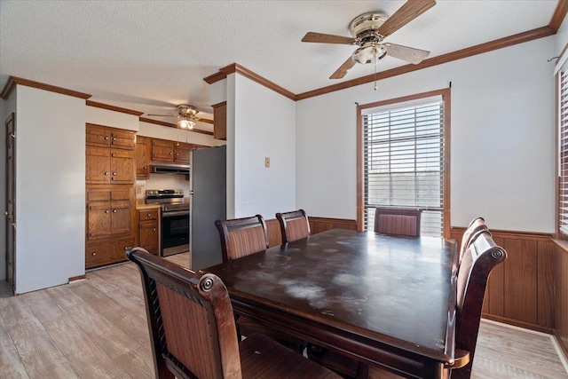 dining area with crown molding, a textured ceiling, light hardwood / wood-style floors, and wood walls