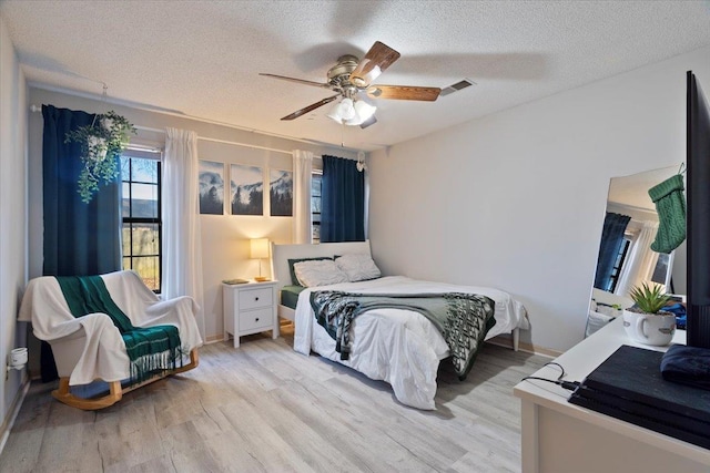 bedroom with ceiling fan, a textured ceiling, and light wood-type flooring