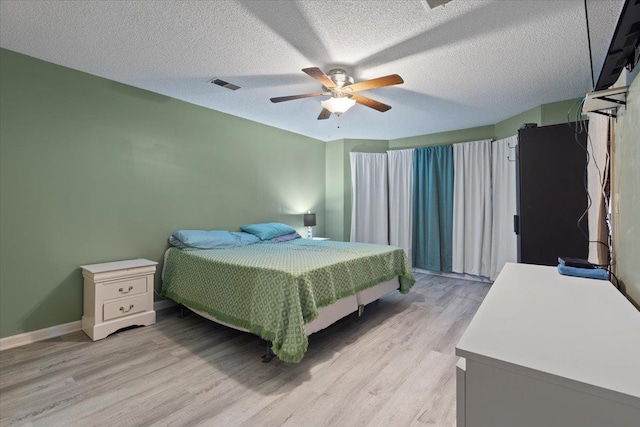 bedroom featuring ceiling fan, light hardwood / wood-style floors, and a textured ceiling