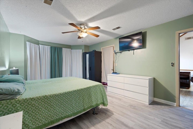 bedroom with ceiling fan, a textured ceiling, and light wood-type flooring