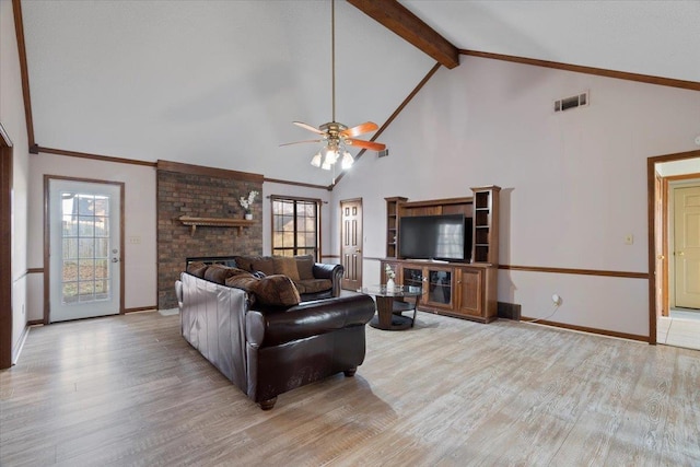 living room with a healthy amount of sunlight, vaulted ceiling with beams, a fireplace, and light hardwood / wood-style floors