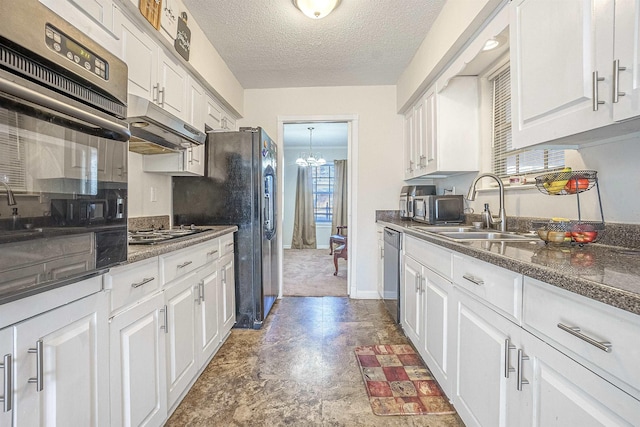 kitchen with dark stone countertops, stainless steel appliances, sink, and white cabinets