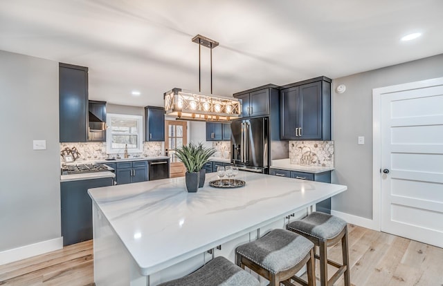 kitchen with a kitchen island, light stone countertops, appliances with stainless steel finishes, and pendant lighting