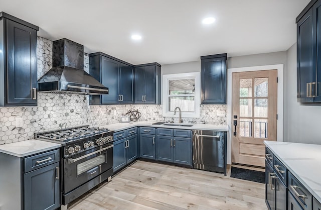 kitchen featuring wall chimney exhaust hood, sink, light stone counters, dishwasher, and high end stove