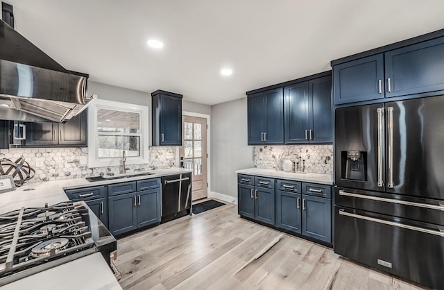 kitchen featuring blue cabinets, extractor fan, sink, light wood-type flooring, and black appliances