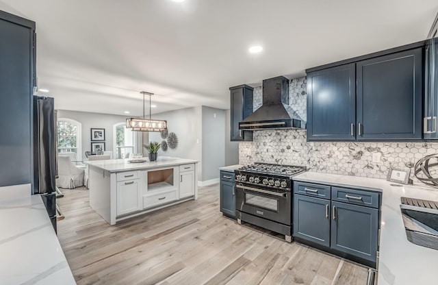 kitchen with high end range, wall chimney exhaust hood, decorative light fixtures, and decorative backsplash