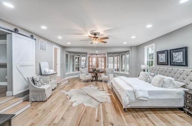 bedroom featuring french doors, ceiling fan, a barn door, and light wood-type flooring