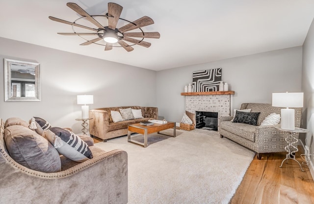 living room with hardwood / wood-style flooring, a tile fireplace, and ceiling fan