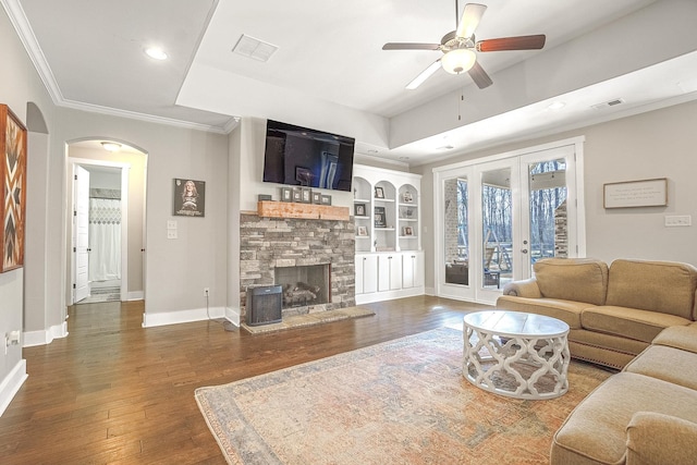 living room featuring french doors, dark hardwood / wood-style flooring, built in features, ceiling fan, and a fireplace