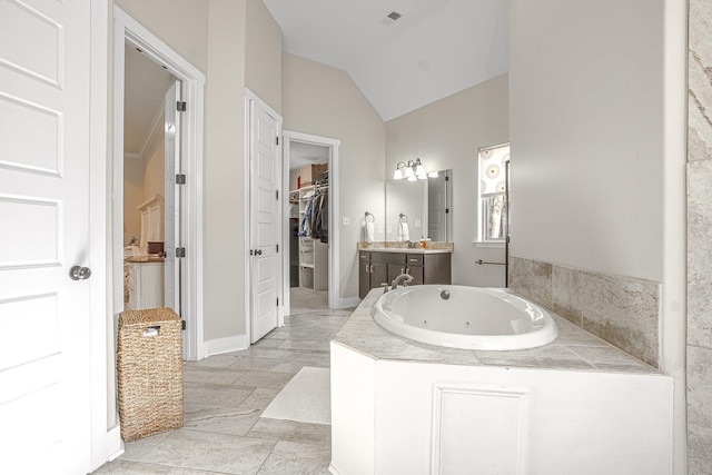 bathroom with vanity, lofted ceiling, and tiled bath