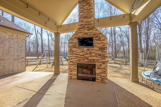 view of patio / terrace with a playground, a trampoline, and an outdoor stone fireplace