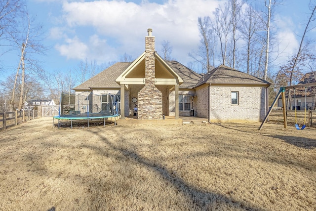 rear view of property with a playground, a trampoline, and a lawn