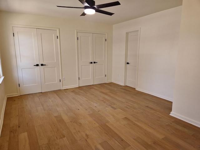 unfurnished bedroom featuring light wood-type flooring, two closets, and ceiling fan