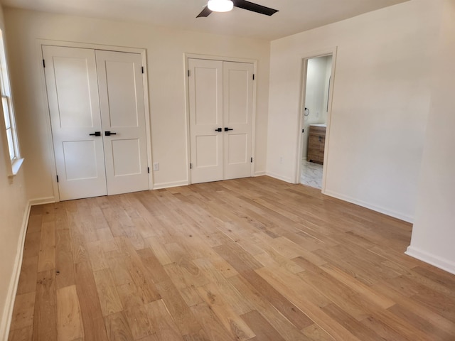 unfurnished bedroom with ceiling fan, light hardwood / wood-style flooring, and two closets