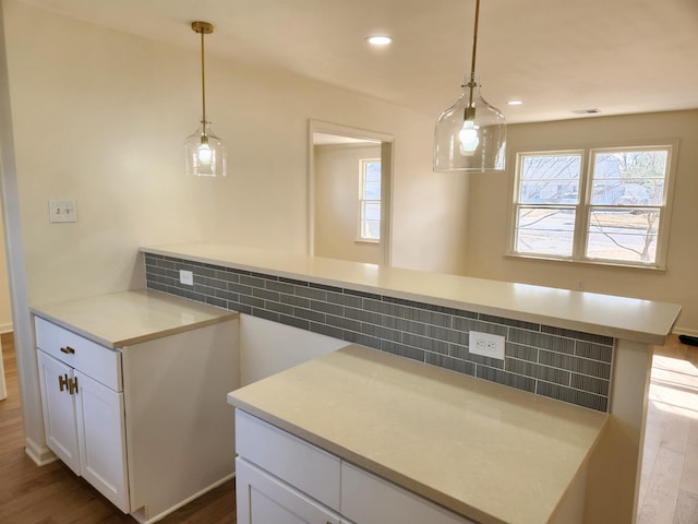 kitchen with hardwood / wood-style flooring, a healthy amount of sunlight, pendant lighting, and white cabinets