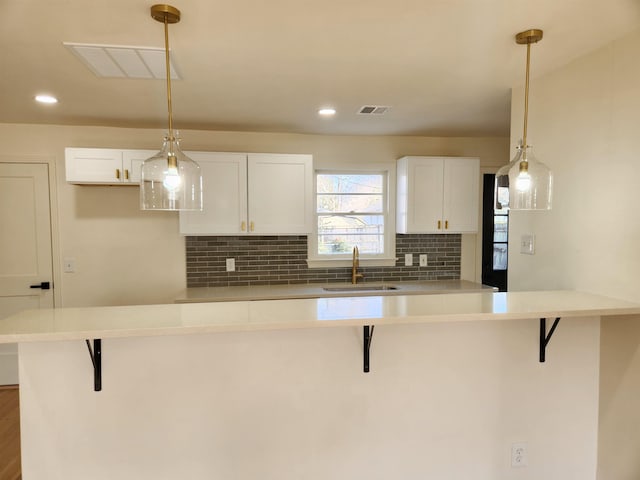 kitchen featuring a kitchen breakfast bar, sink, and white cabinets