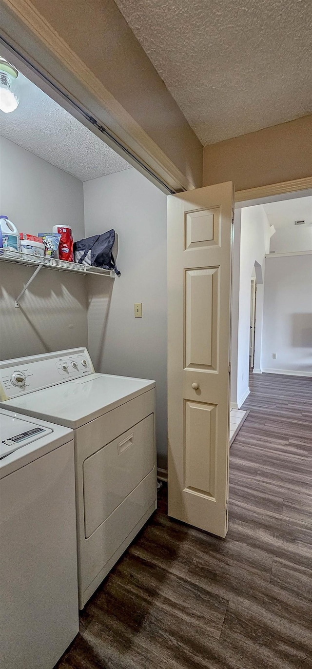 clothes washing area featuring dark hardwood / wood-style floors, washing machine and clothes dryer, and a textured ceiling