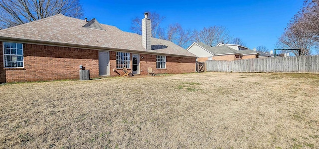 rear view of house featuring central AC and a yard