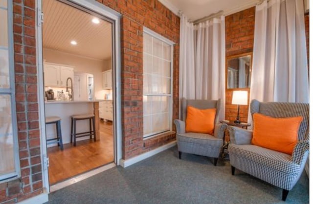 living area with dark colored carpet and brick wall