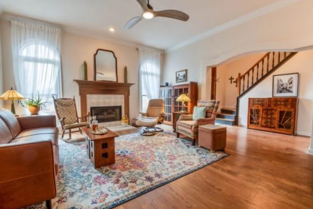 living room with crown molding, ceiling fan, a fireplace, and hardwood / wood-style floors