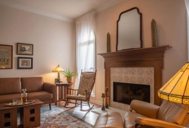 living area featuring crown molding, a fireplace, and hardwood / wood-style flooring