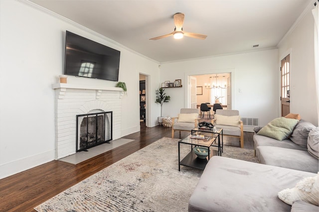 living room featuring ornamental molding, ceiling fan with notable chandelier, a fireplace, and dark hardwood / wood-style flooring