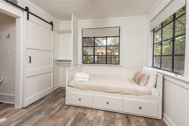 bedroom with wood-type flooring and a barn door