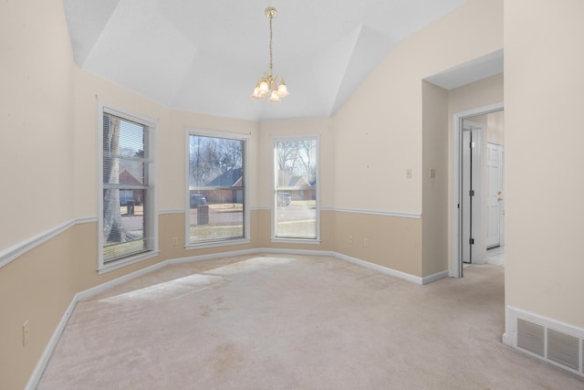 carpeted empty room featuring lofted ceiling and a notable chandelier