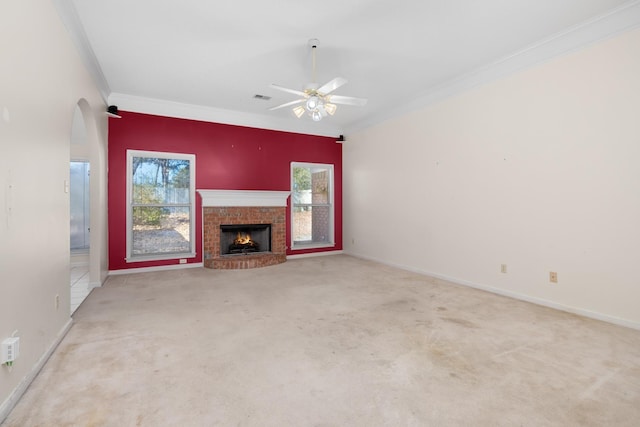 unfurnished living room featuring ceiling fan, light colored carpet, ornamental molding, and a brick fireplace