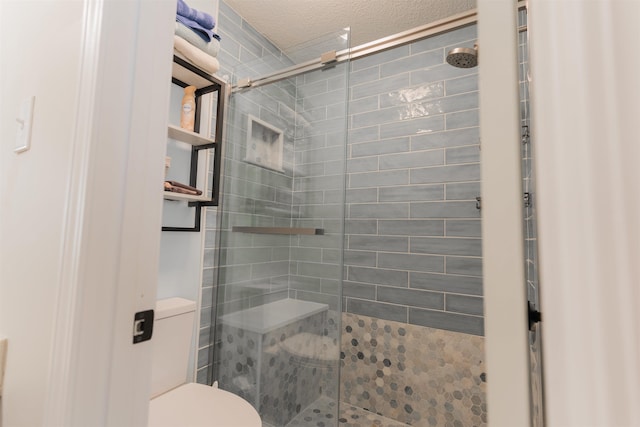 bathroom with toilet, a shower with shower door, and a textured ceiling