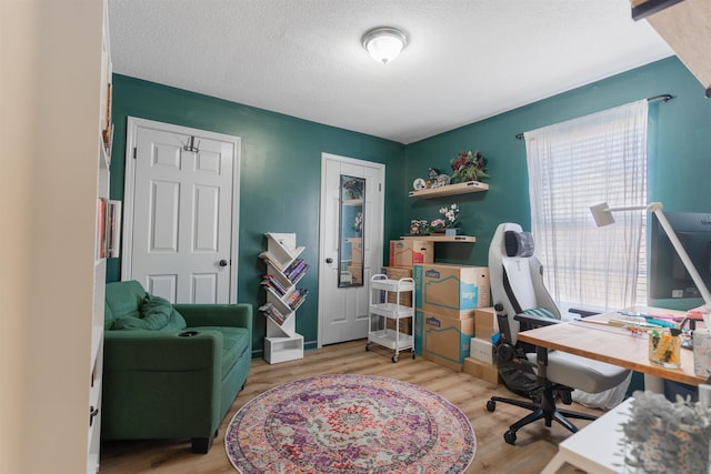 home office with a wealth of natural light, a textured ceiling, and light wood-type flooring