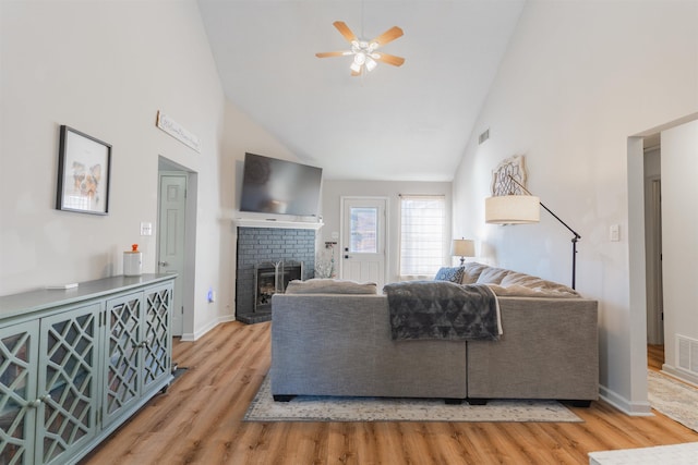 living room featuring ceiling fan, a fireplace, high vaulted ceiling, and light hardwood / wood-style flooring