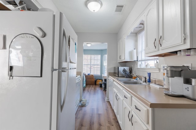 kitchen with white cabinetry, plenty of natural light, sink, and white appliances