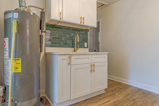 interior space featuring backsplash, white cabinets, light hardwood / wood-style flooring, and gas water heater