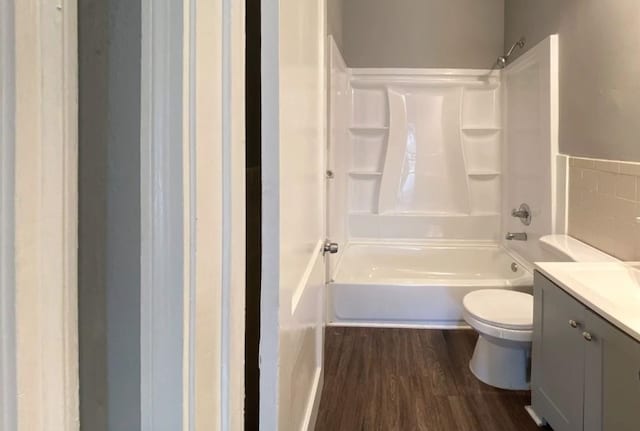 full bathroom featuring hardwood / wood-style floors, tile walls, vanity,  shower combination, and toilet