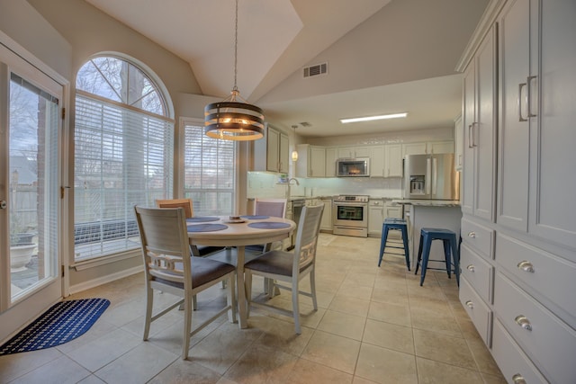 tiled dining area with lofted ceiling and sink