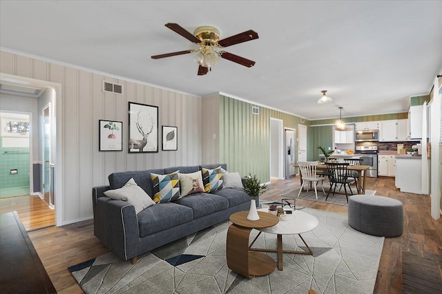 living room featuring visible vents, crown molding, and light wood finished floors