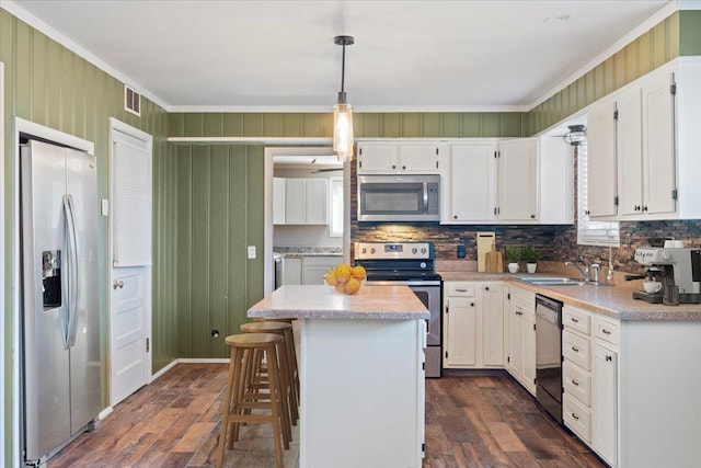 kitchen with white cabinetry, hanging light fixtures, appliances with stainless steel finishes, light countertops, and a center island